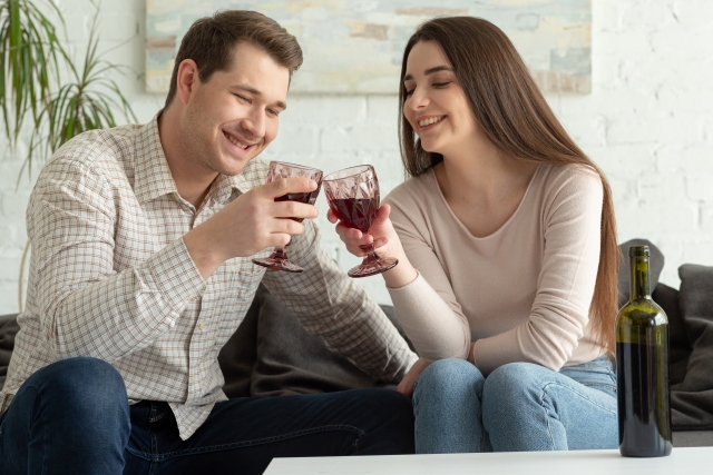 家でお酒を飲んでいるカップルの写真